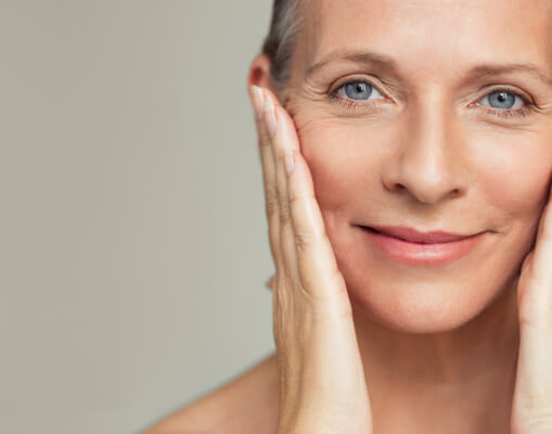middle aged woman's face posing holding her wrinkles 