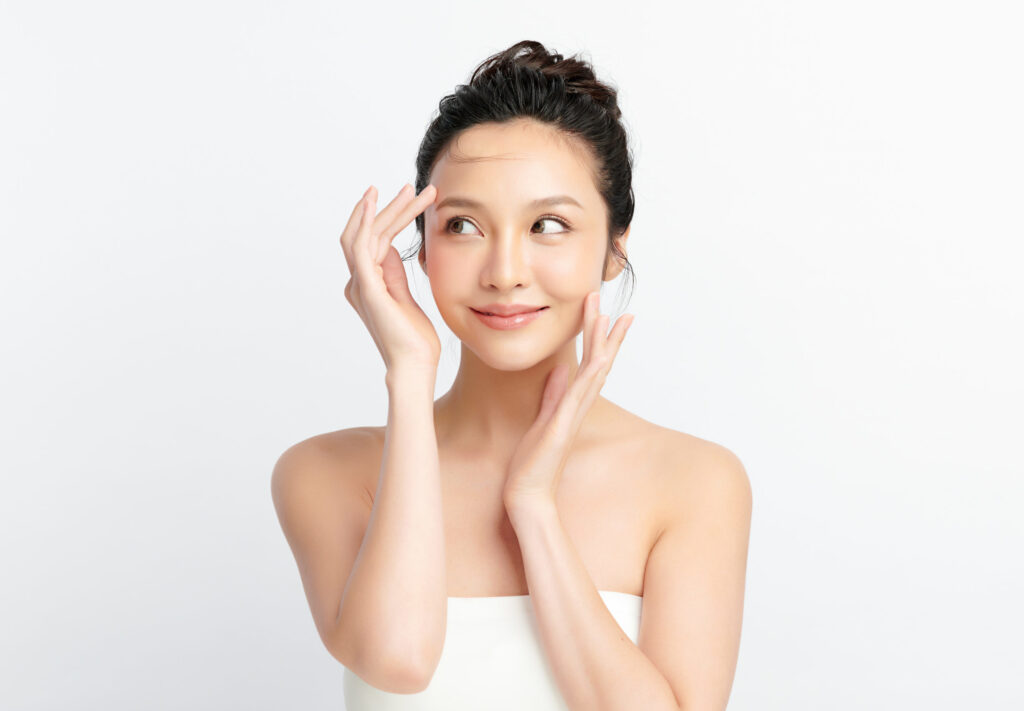 young woman wearing a towel posing smiling and touching her face